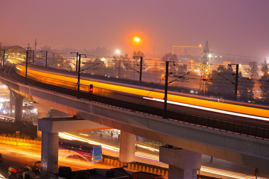 What Makes Delhi the Most Reborn City in the World Dynamic night view of a modern city with illuminated train tracks showcasing speed and urban life.